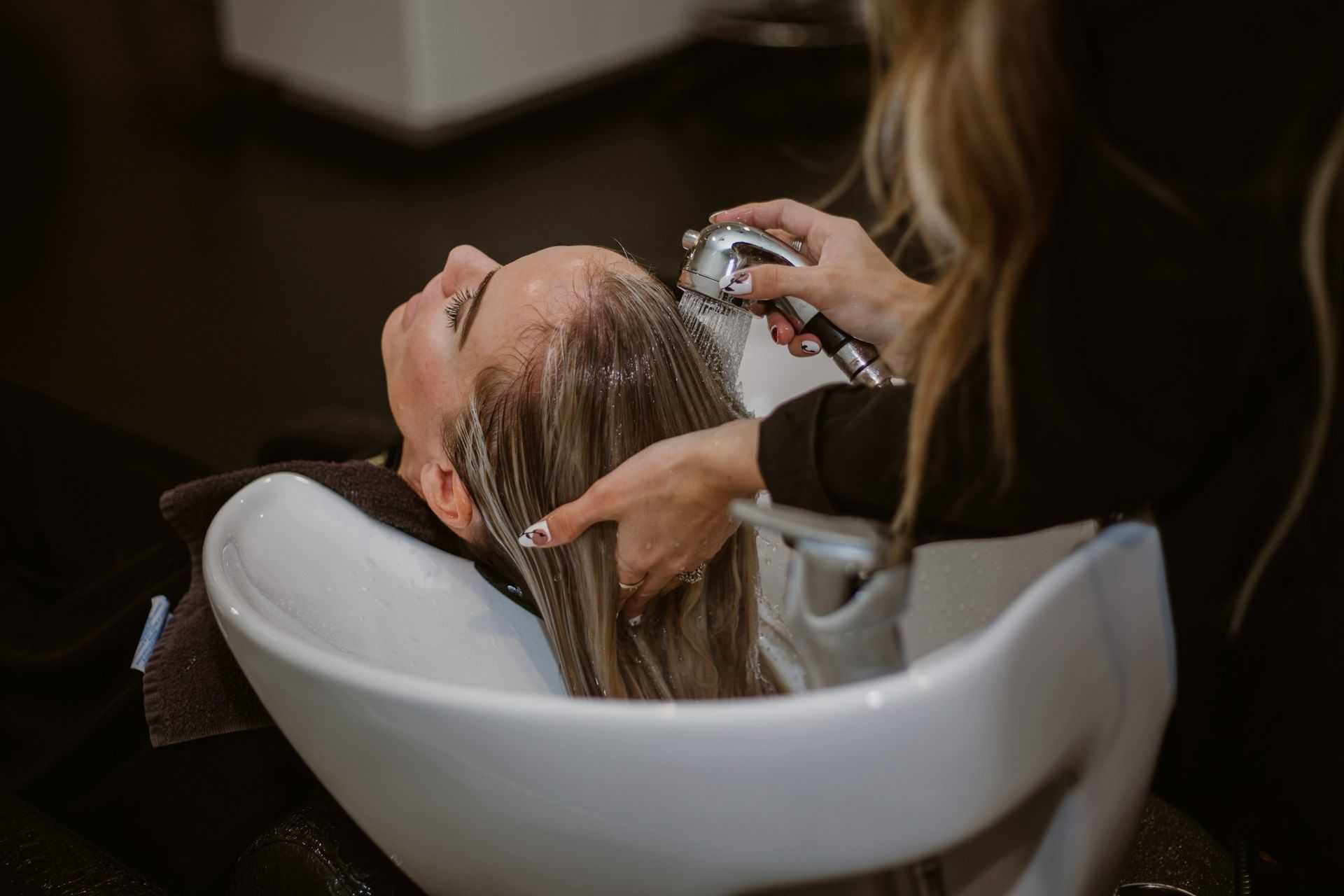 Person receiving a hair wash at a salon sink by a hairdresser.